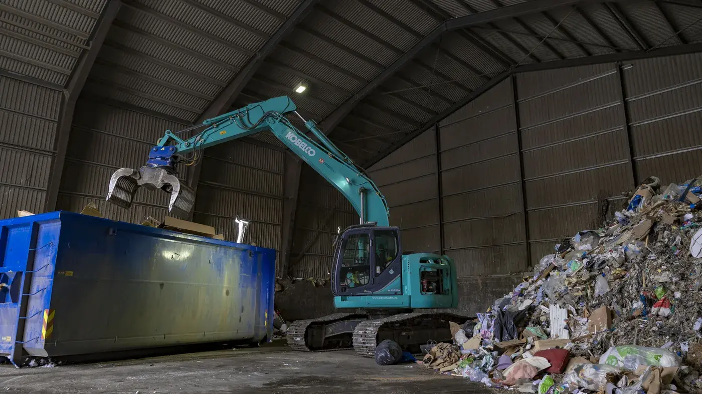 Materialhåndterer og blå container inne i hallen på Moane